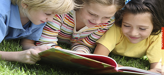 Three children share a book together.